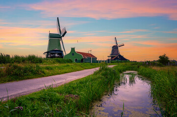 Sunset above historic farm houses and windmills in the beautiful holland village of Zaanse Schans near Amsterdam in the Netherlands. - obrazy, fototapety, plakaty