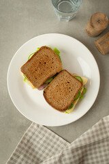 Sandwich with mortadella, cheese and tomatoes on a gray table