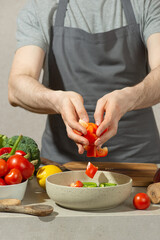 A man in a gray kitchen apron prepares a salad, close-up