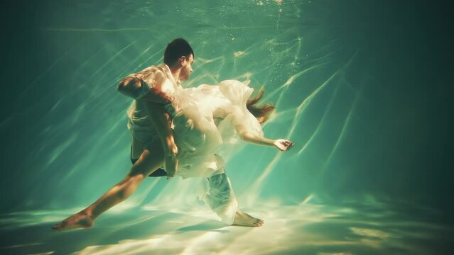 Happy fantasy couple fall in love swim dive man king and woman fashion model posing underwater dark blue sea. Wet white dress. fairy sexy girl Muse river nymph swims hugs guy magic under water pool 4k
