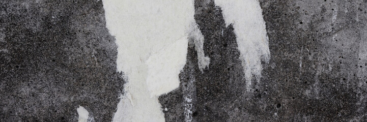 Torn old faded paper wallpaper on a concrete wall. Ragged scraps of white paper on a gray background. Vintage texture for background and design. Closeup view with copy space for text.