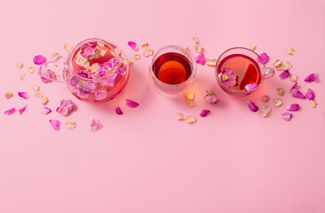 tea with rose petals in glass teapot on pink background