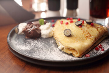 Pancakes with cottage cheese, served with fresh fruit, whipped cream and chocolate, close-up, selective focus. 