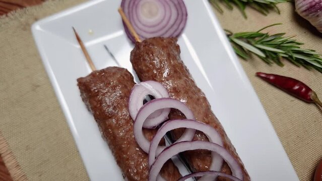 Baked lula kebab on rectangular dish on a rustic table