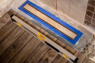 Linear floor level shower. Wood effect ceramic tile and modern metallic linear drain installation...
