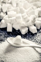 Concept with white unhealthy sugar. Sugar cubes and crystals on a wooden table.