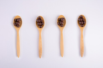 Chocolate balls on wooden spoon on a white background.
