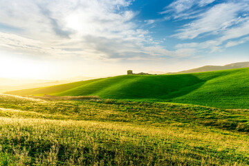 Fototapeta premium scenery rural view of a contryside farm in green fields and hills with amazing cloudy sky on background