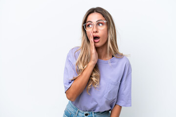 Young Uruguayan woman isolated on white background whispering something with surprise gesture while looking to the side