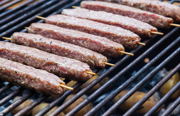 Raw minced meat, grilled on wooden skewers. Lula Kebab on a grill grid.