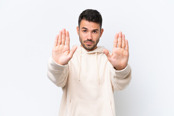 Young caucasian man isolated on white background making stop gesture and disappointed