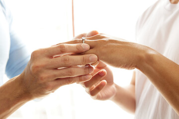 close up young gay couple wearing engagement ring to finger