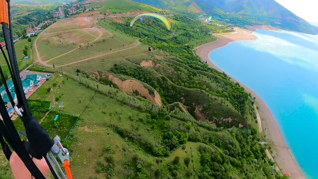 paragliding in Uzbekistan. paraglider flying away over the Amirsoy ski slope and Charvak lake from right to left. Extreme and active types of recreation. panoramic view from gopro. High quality FullHD