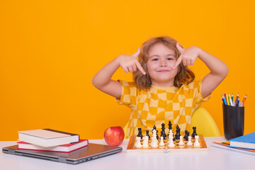 Clever child thinking about chess. Portrait of clever kid with chessboard. Boy play chess. Kid with chess on yellow isolated studio background.