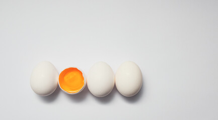 Row of white eggs and single broken egg with a yolk.