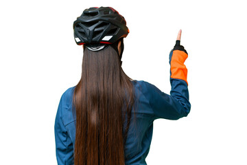 Young cyclist woman over isolated chroma key background pointing back with the index finger - obrazy, fototapety, plakaty