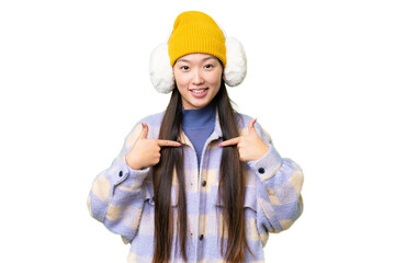 Young Asian woman wearing winter muffs over isolated chroma key background with surprise facial...