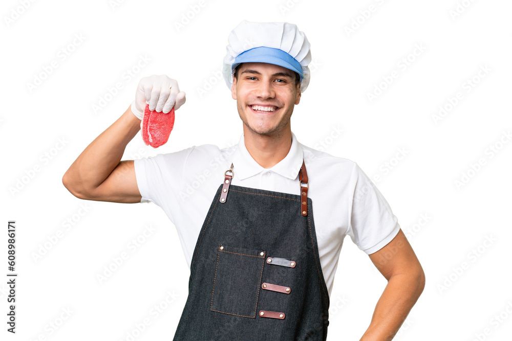 Wall mural Butcher caucasian man wearing an apron and serving fresh cut meat over isolated background posing with arms at hip and smiling