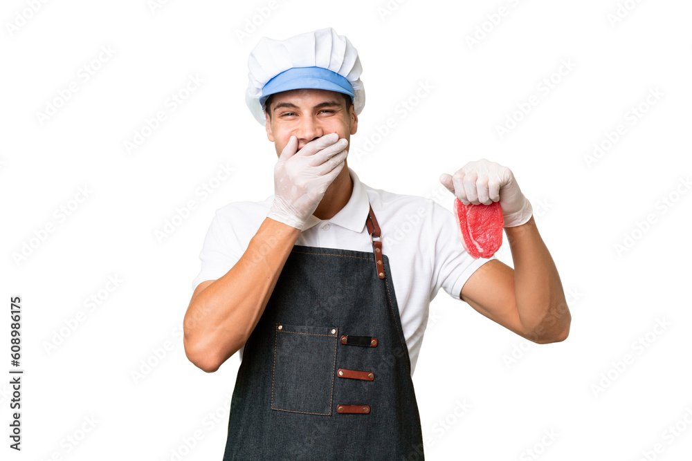 Wall mural Butcher caucasian man wearing an apron and serving fresh cut meat over isolated background happy and smiling covering mouth with hand