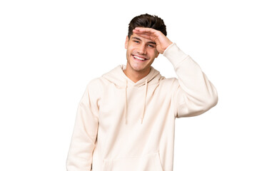 Young caucasian handsome man over isolated background looking far away with hand to look something