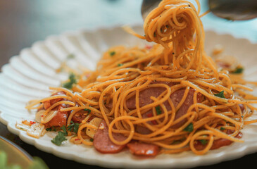 Dried chilli sausage spaghetti on a fork and a white plate.