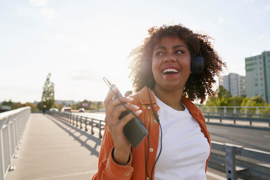 Black woman wearing headphones and walking on the bridge