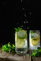 Cold lemonade with mint and lemon and ice on a dark background