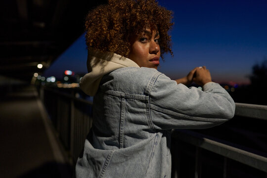 Black woman standing on the bridge at night and looking at camera