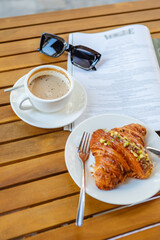 Morning coffee and croissant with reading material