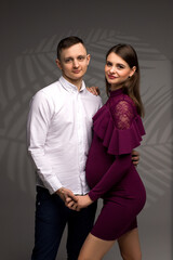 pregnant couple on a grey background, studio pregnancy shoot