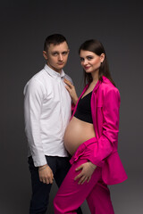 Pregnant couple on a gray background close-up. Belly of a pregnant woman in close-up. Portrait of a pregnant couple.