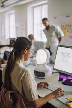 Side view of female student using computer while sitting at desk