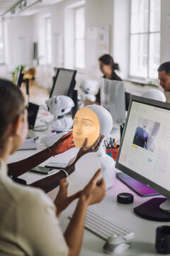 Female PhD students discussing over social robot while sitting at desk in innovation lab