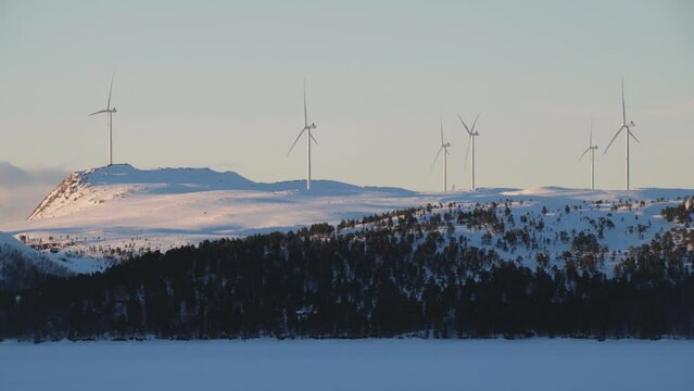 Lot of spinning wind turbines on top of a mountain in Norway. Modern devices that generate environmentally friendly electricity on a sunny winter evening