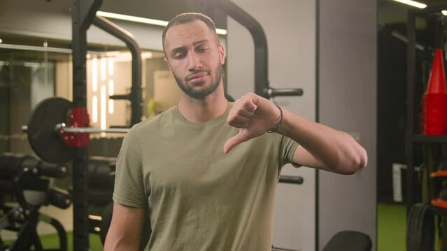 Sad upset dissatisfied loser bodybuilder African American man showing thumb down bad result unmotivated disagree dislike in gym sport failure fitness guy hard ineffective exercise workout athlete fail