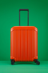 Travel orange color suitcase on a green background. Travel and vacation concept in triples. Stylish Trolley suitcase on color background. Space for text. 