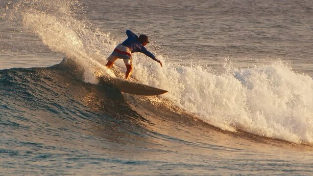 Male surfer rides the wave in the ocean and does sharp turn