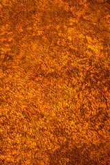 Golden wall with abstract spots as a background. Beautiful golden texture with patterns, decorative plaster. Modern bright wall painting in trendy shades, unusual spotted yellow and gold surface.