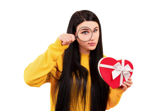 girl in a yellow pullover with a magnifying glass in hand and a gift in the shape of a heart, a concept search surprise isolated on transparent background