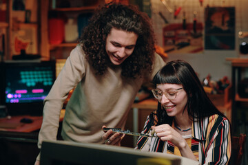 Young smiling people working with computer chip and developing new computer during teamwork in...