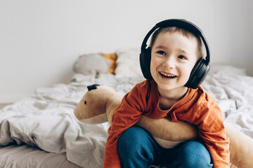 Stylish teen boy listening music in headphones and smiling. Happy child listening loud music in...
