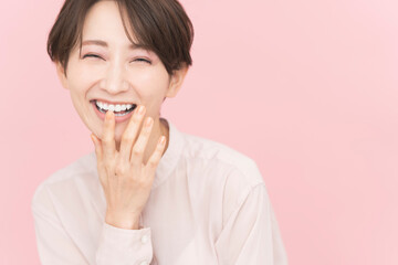 笑顔のショートヘアの日本人女性/ピンク背景のビューティーポートレート