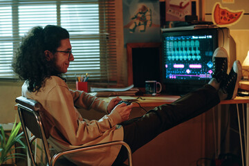 Guy sitting on chair and playing video game console during his leisure time © pressmaster