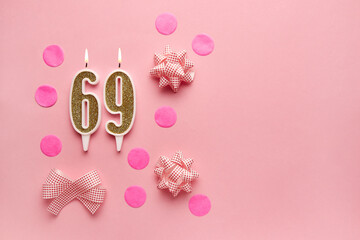 Number 69 on pastel pink background with festive decor. Happy birthday candles. The concept of...