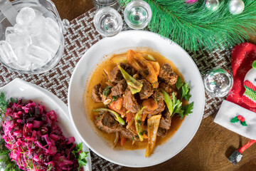 Beef stew with carrots, onions, peas and russian herring under fur salad near. View from above.