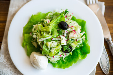 fresh summer salad with early cabbage, cucumbers, radishes and other vegetables in a plate