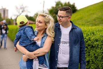 Obraz premium Family walking in the park with the curious child in their arms