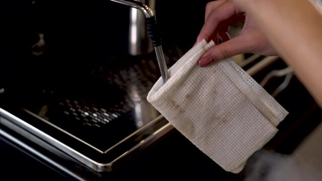 Woman hand clean coffee machine after using, staff or small business owners prepare to steam the milk foam for cappuccino hot cup, staff or barista take care of the equipment in the cafeteria