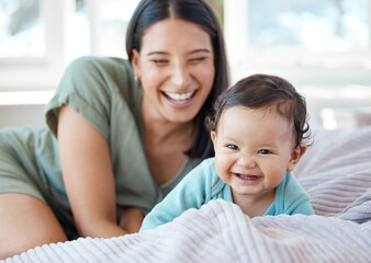 Mother, laughing baby and play on bed in home for love, care and quality time together with joy,...