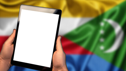 Man hold tablet phone pc gadget with white blank screen, copy space for text, image or message. Flag of Comoros country on background. Technology, information, business

